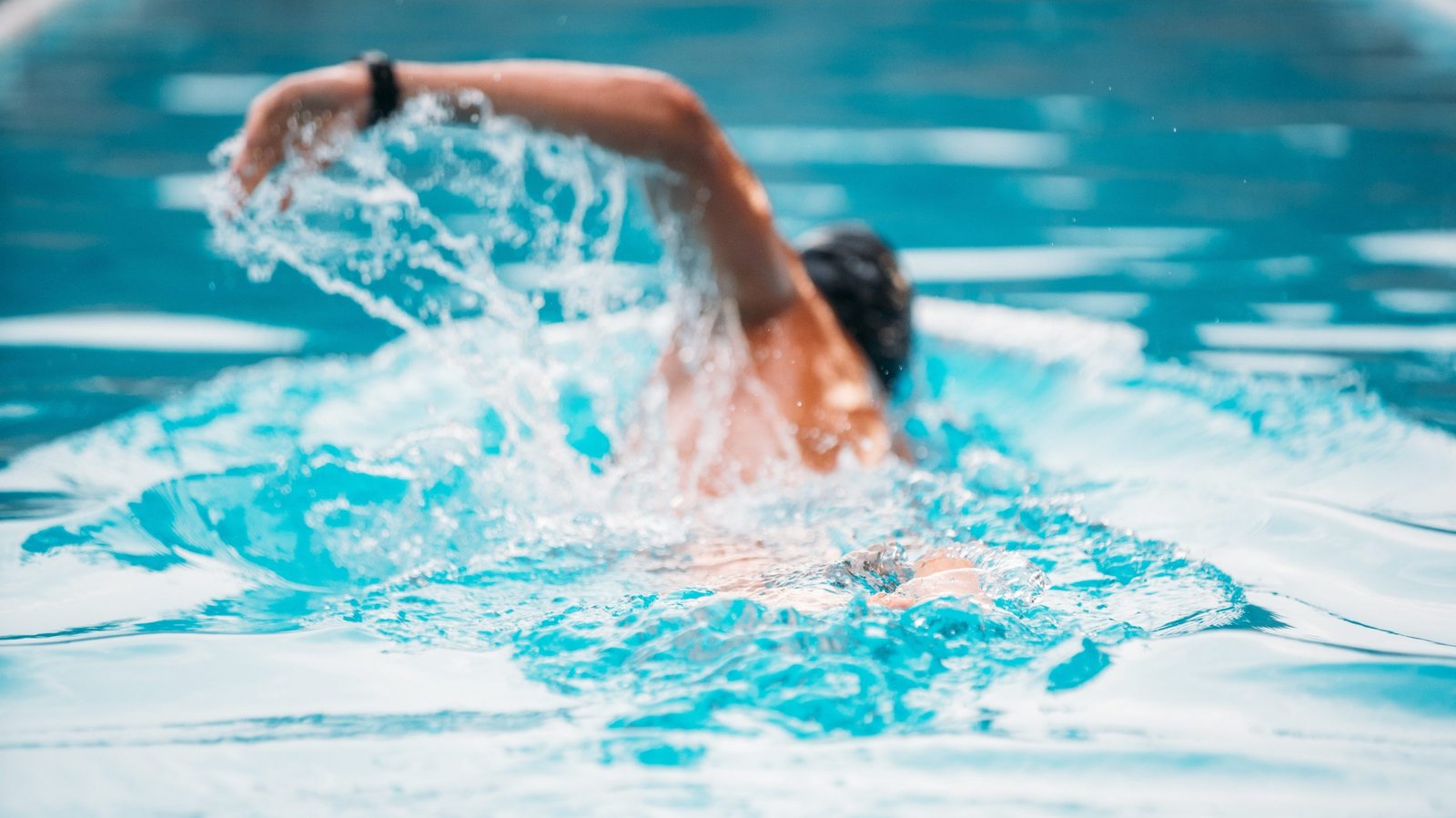 Athletic Young man swimming the front crawl in a pool. 